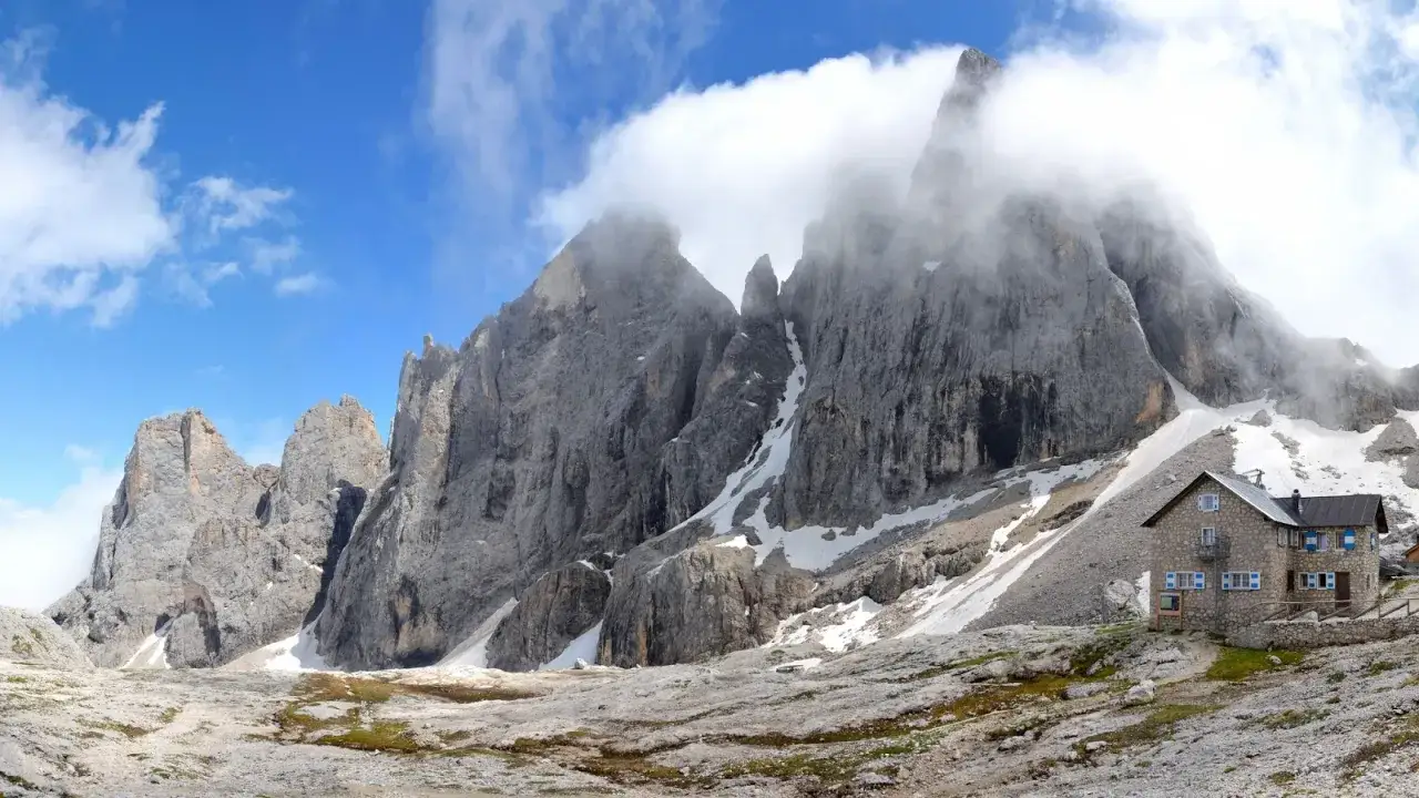 Rifugio Mulaz da Passo Valles, un'oasi di pietra tra le vette dolomitiche avvolte dalle nuvole.