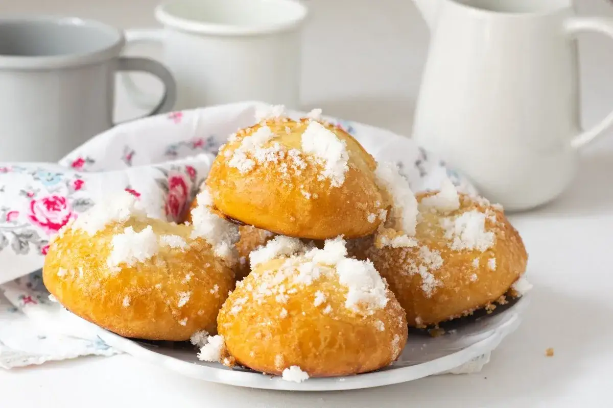 Bollos suizos dorados y esponjosos, espolvoreados con azúcar, listos para disfrutar con café.