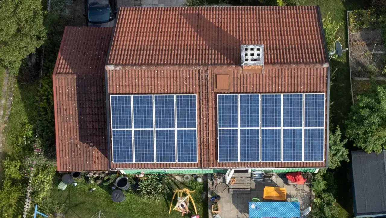 En liten solcellsanl&auml;ggning p&aring; ett tegeltak. Tv&aring; rader med solpaneler f&aring;ngar solens energi.