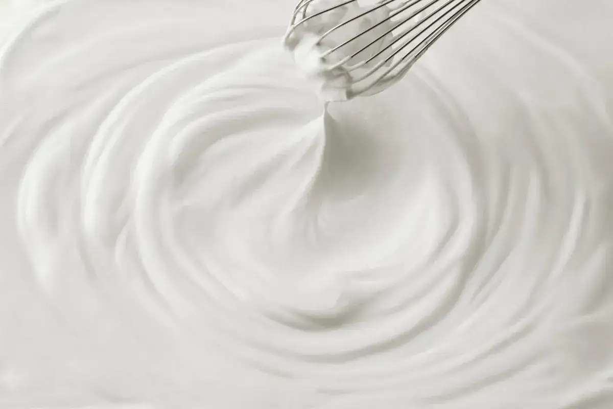 Un fouet en train de battre de la chantilly maison, cr&eacute;ant des vagues douces et a&eacute;riennes dans la cr&egrave;me.