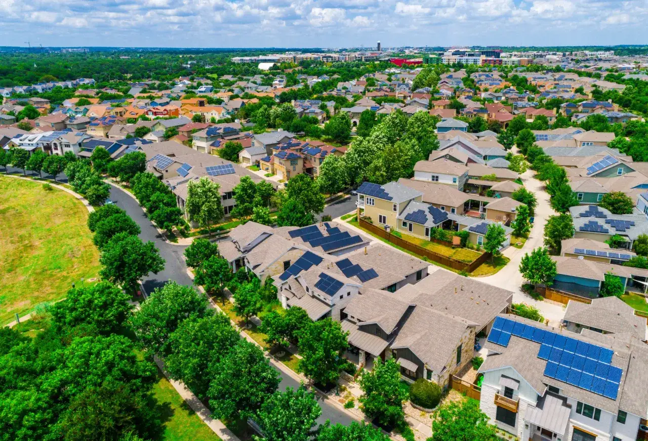 A suburban neighborhood with many houses featuring solar panels, showcasing sustainable urban planning.