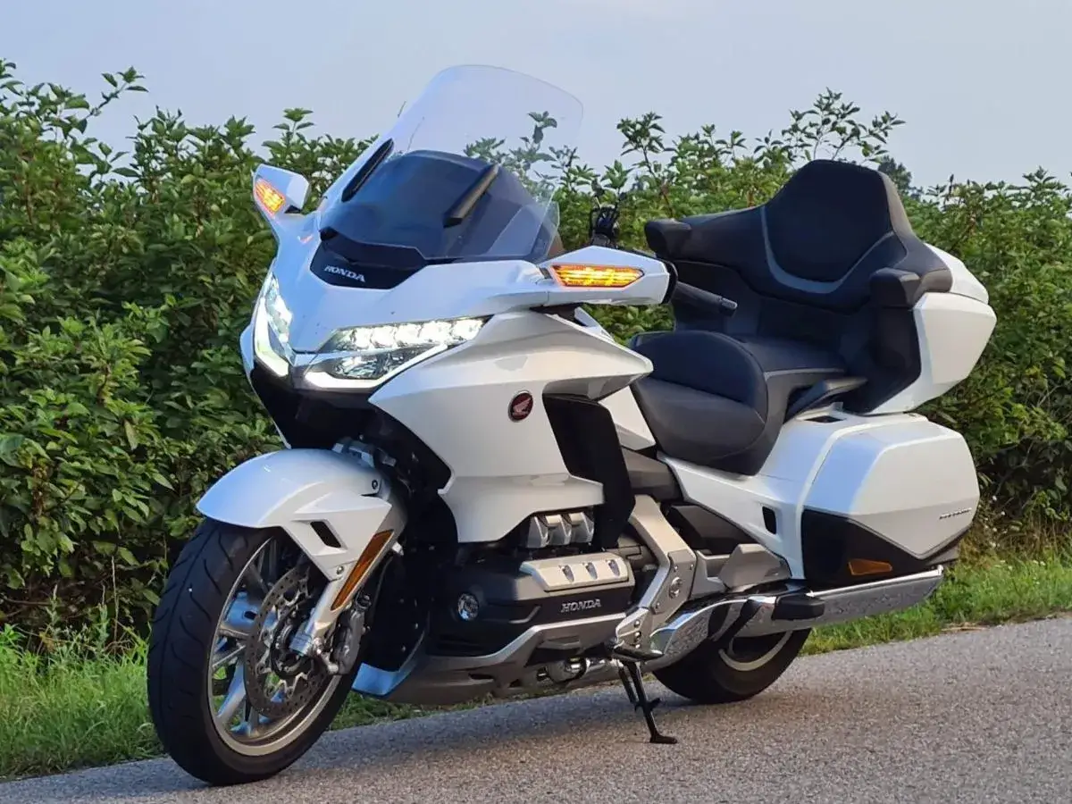 Biały Honda Goldwing 1800, lśniący na tle zieleni. Choć jego wady są dyskusyjne, komfort i moc tego turystycznego giganta robią wrażenie.