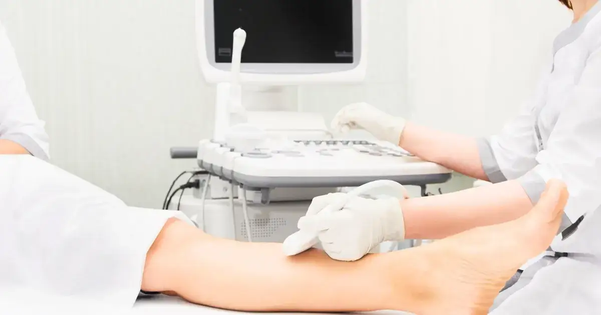 Lekarz wykonujący USG Doppler nogi, pacjent na leżance