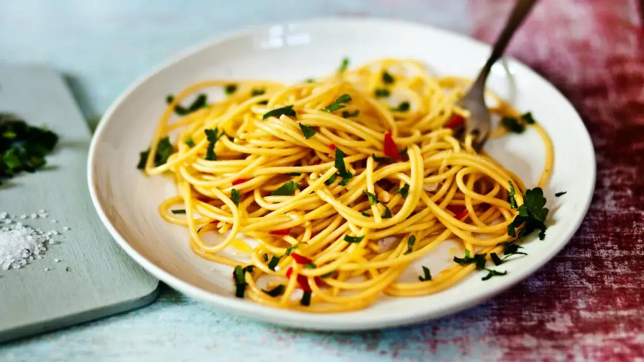 Ein Teller mit köstlichen Spaghetti Aglio e Olio, garniert mit Petersilie und Chili.