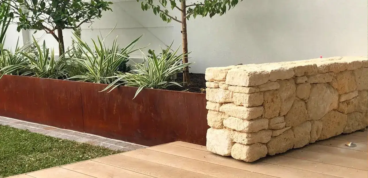 Moderne Rasenkante Ideen: Rostiger Stahlrahmen mit Ziergr&auml;sern und eine Trockenmauer aus Naturstein.