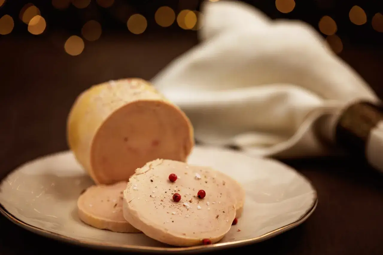 Un délicieux foie gras, spécialité Dordogne, finement assaisonné de sel et de poivre rose, prêt à être dégusté sur une assiette élégante.
