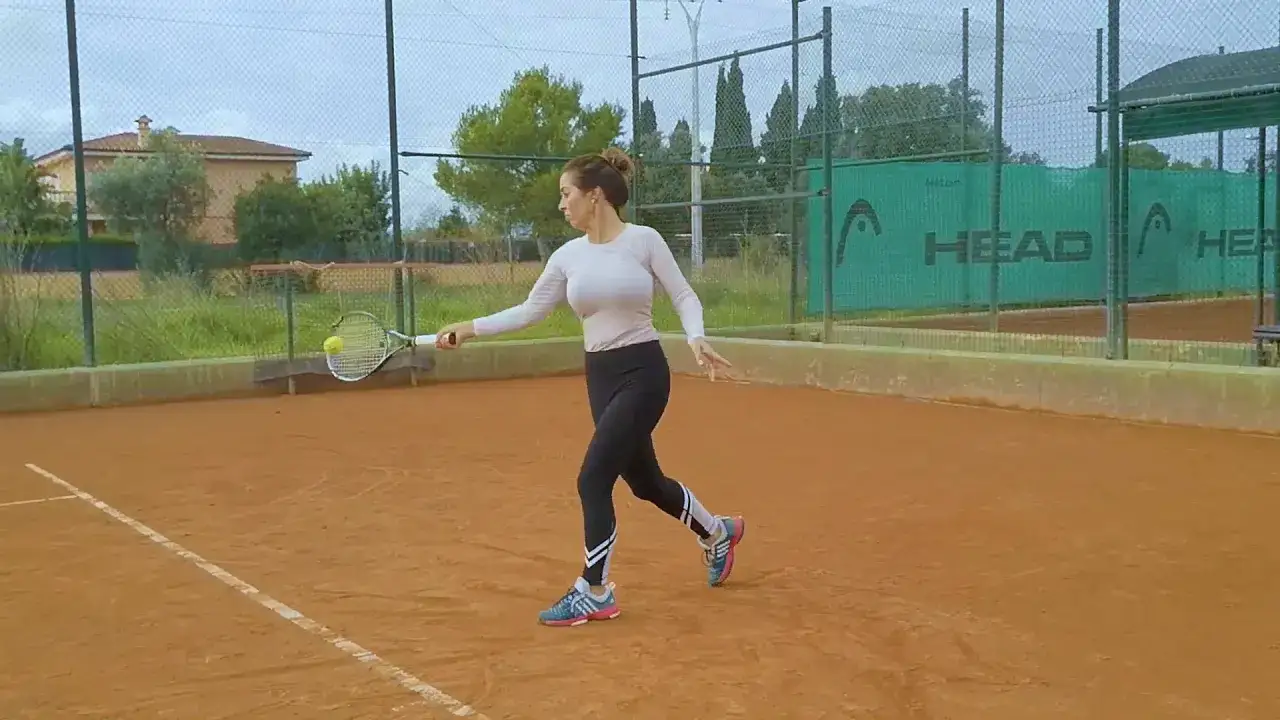 Kobieta na korcie tenisowym wykonuje uderzenie forehand.