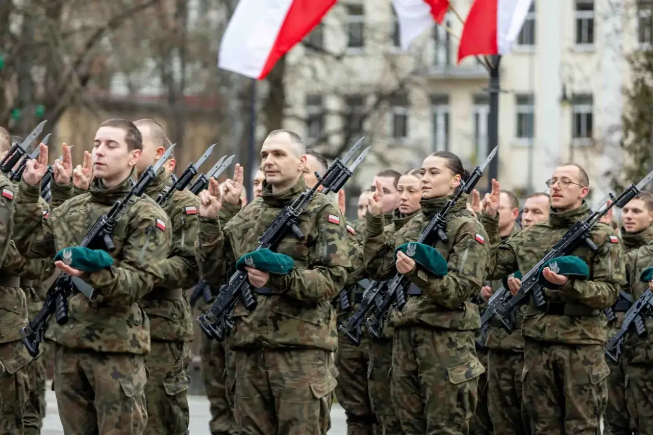 Żołnierze w mundurach, z karabinami i zielonymi beretami, podnoszą ręce. Może to zapowiedź podwyżek dla wojska w 2026 roku.