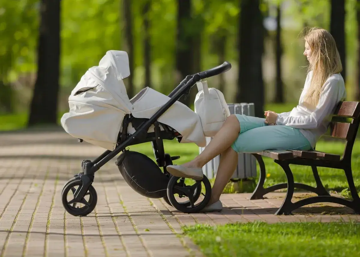 Prawda o nianiach u celebrytów: ile zarabiają i jakie mają wymagania. Kobieta z wózkiem w parku.