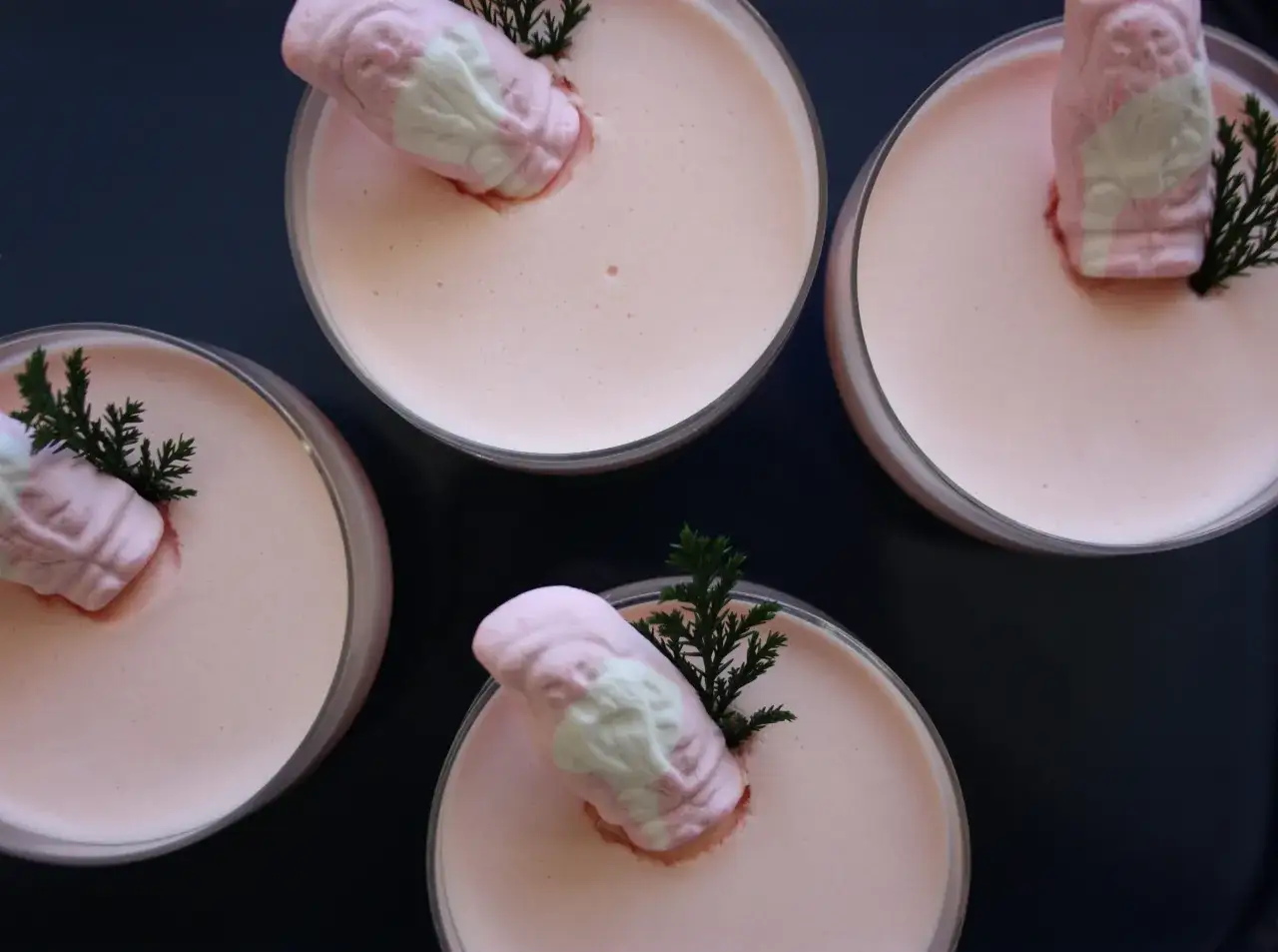 Fyra glas med rosa mousse, dekorerade med skumtomtar och granris. Perfekt f&ouml;r att baka skumtomtar till jul.