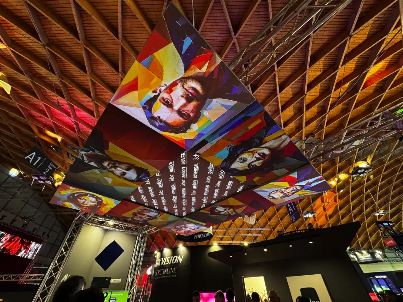 Installazioni artistiche colorate con volti umani dominano il soffitto di un padiglione fieristico a MIR Rimini.