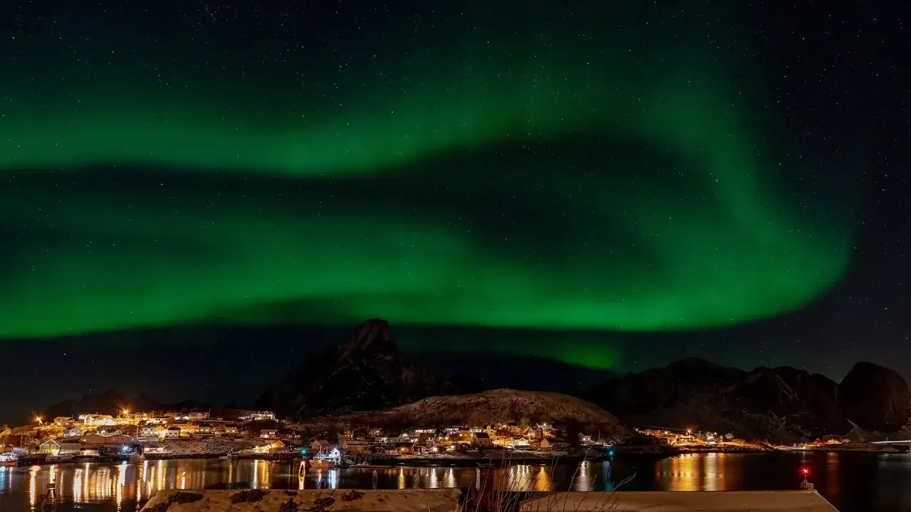 Magiskt norrsken över en by vid vattnet på Lofoten. En dröm att se detta ljusspel.