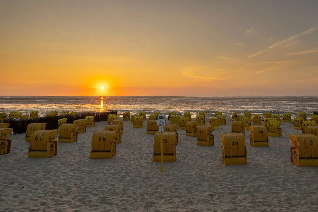 Sonnenuntergang &uuml;ber dem Duhnen Strand mit vielen gelben Strandk&ouml;rben.