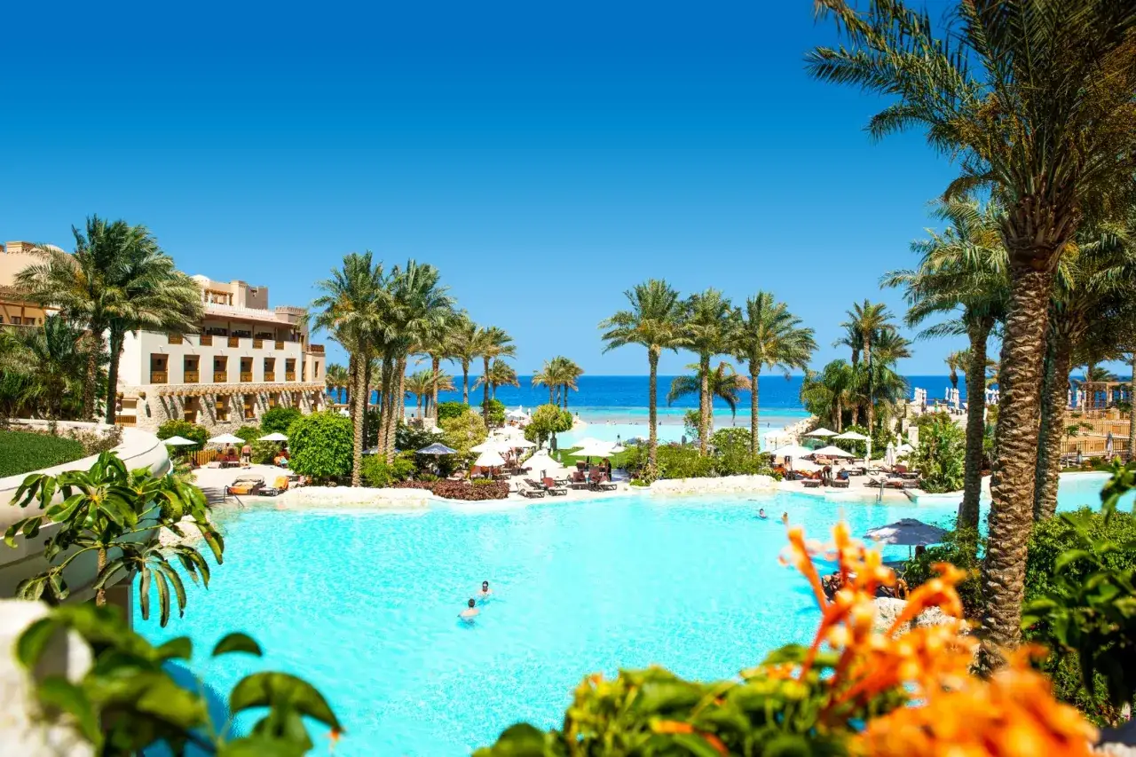Słoneczny dzień w Makadi Bay. Lazurowa woda basenu, palmy i hotel w tle.