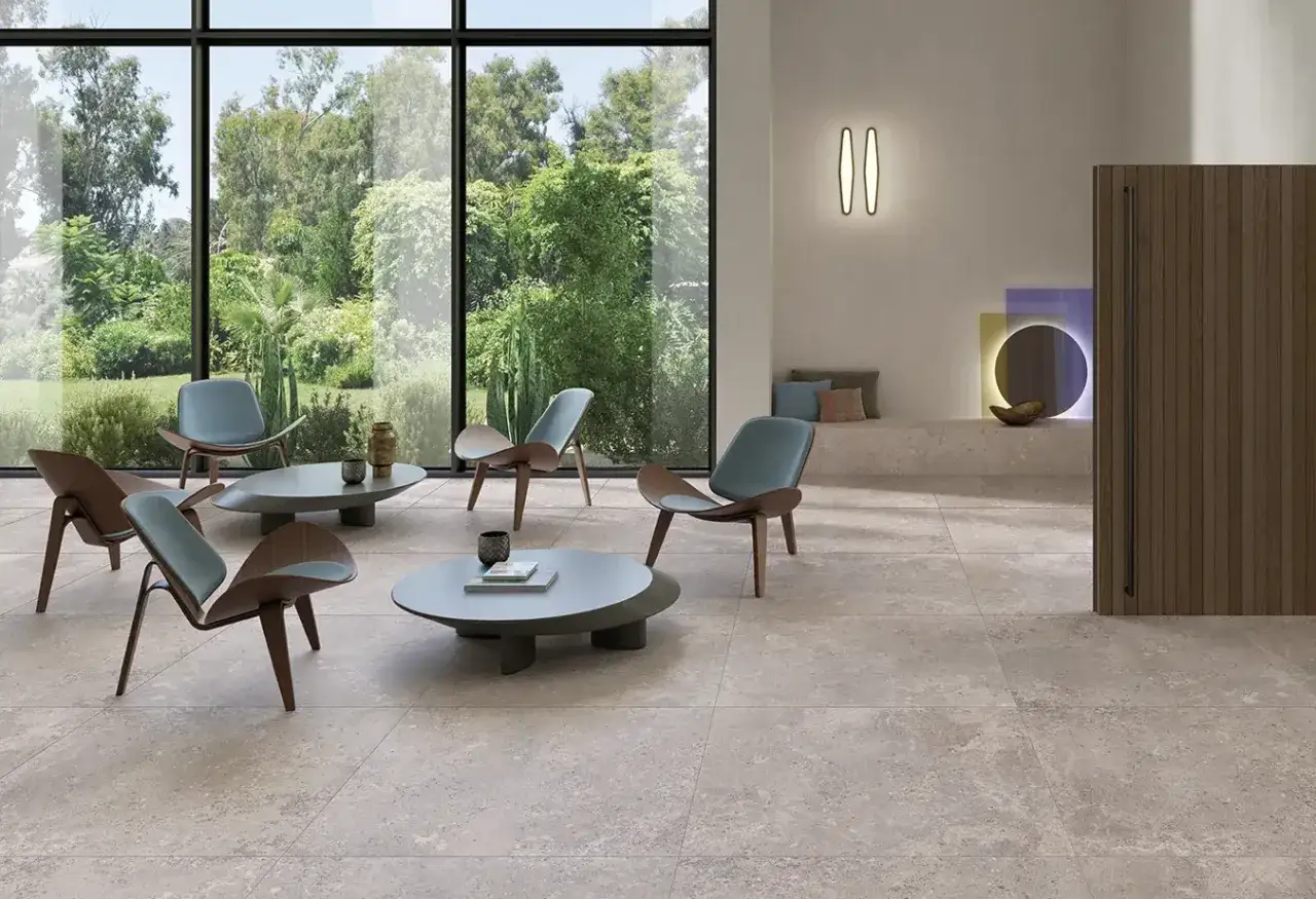Un salon moderne avec des chaises design et des tables basses, le tout sur un carrelage pi&egrave;ce de vie tendance. La lumi&egrave;re naturelle inonde l'espace gr&acirc;ce aux grandes baies vitr&eacute;es.