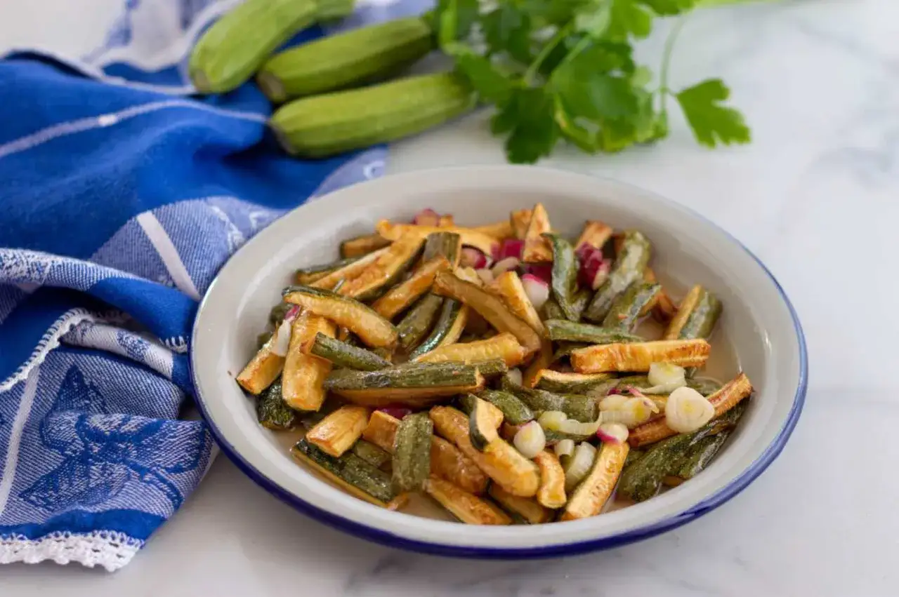 Zucchine in carpione, un contorno saporito e colorato, con cipolla e ravanelli, pronto per essere gustato.