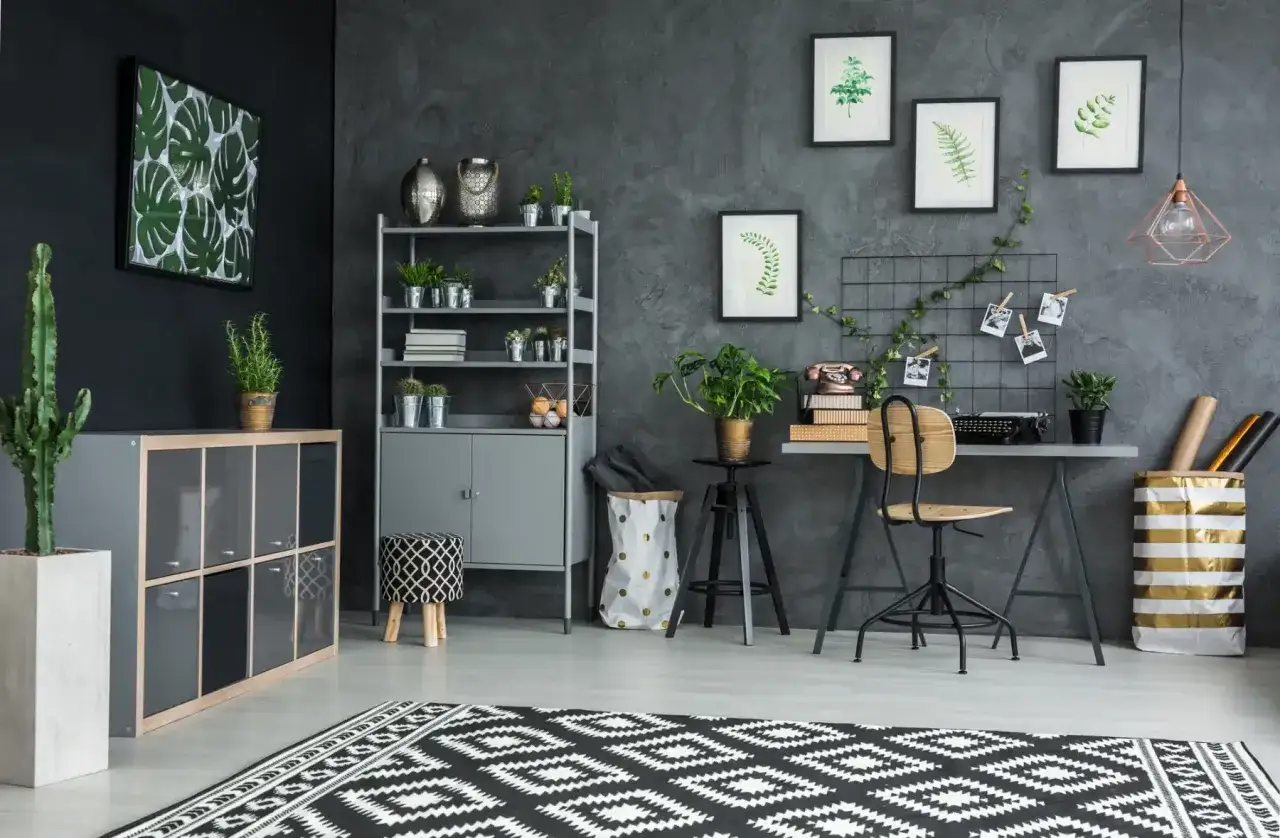 Ein Arbeitsplatz mit Pflanzen und Vintage-Elementen. Die graue Wand mit Struktur ist ein toller Hintergrund, aber **warum Tapete**? Ein Bild mit Monstera-Blättern und ein Teppich mit geometrischem Muster.