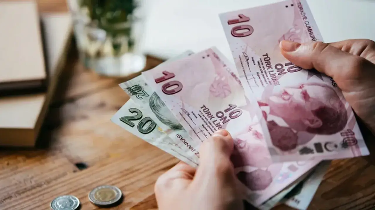 Dłoń trzyma banknoty 10 i 20 lir tureckich. Kurs waluty Turcji jest zmienny.