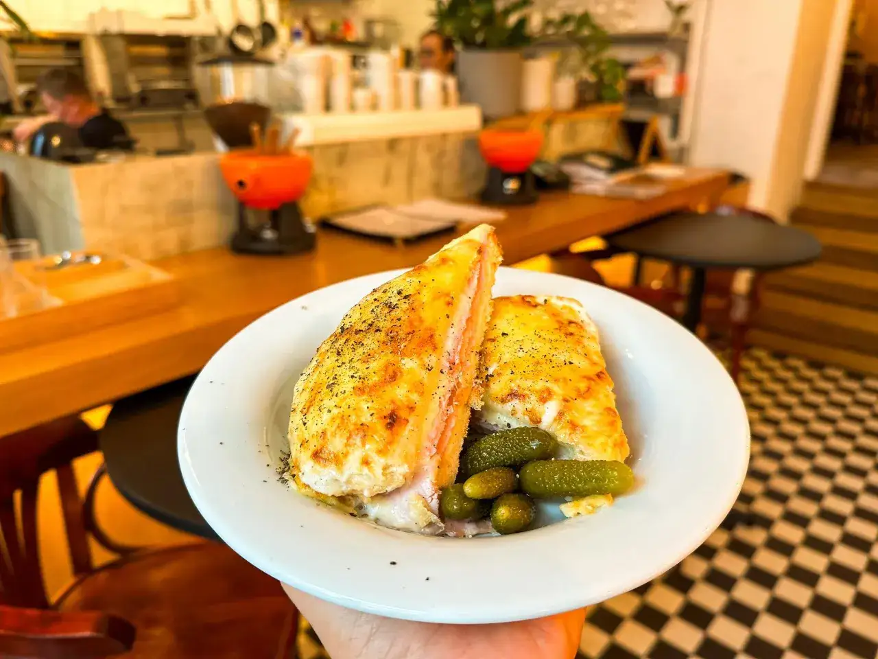 Pyszna zapiekanka z szynką i serem, podana z ogórkami konserwowymi. Idealne danie do bistro, gdzie liczy się smak i szybkość.