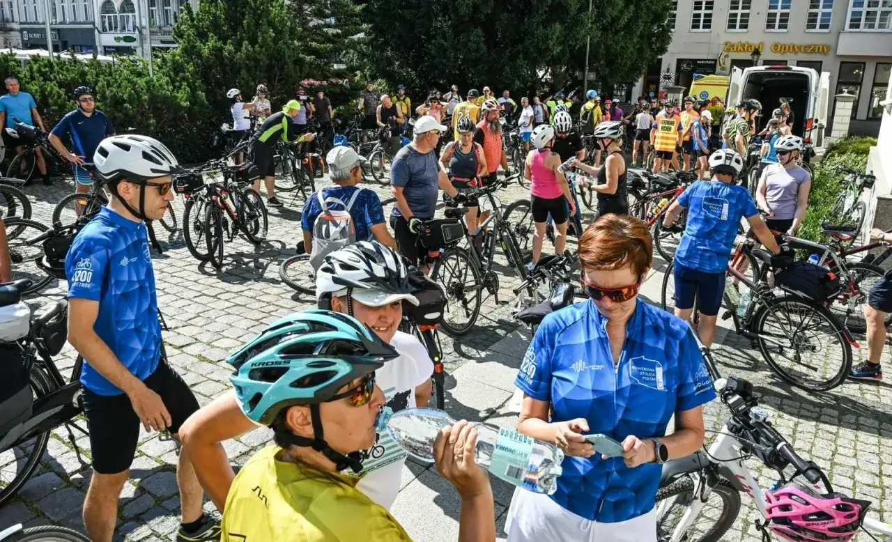 Uczestnicy rajdu rowerowego w kaskach i strojach sportowych, gotowi do startu.
