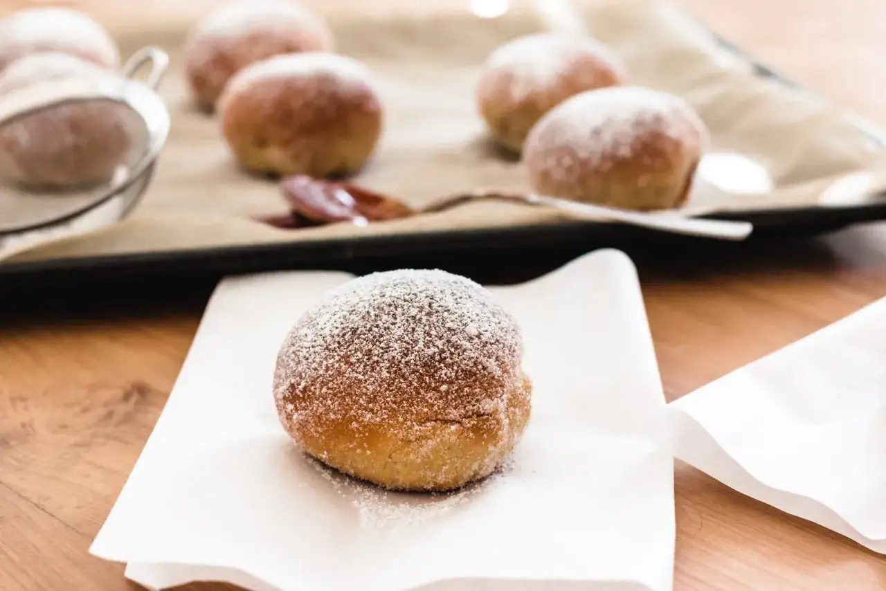 Frisch zubereitete berliner im airfryer, mit Puderzucker best&auml;ubt, liegen auf einem Backpapier.