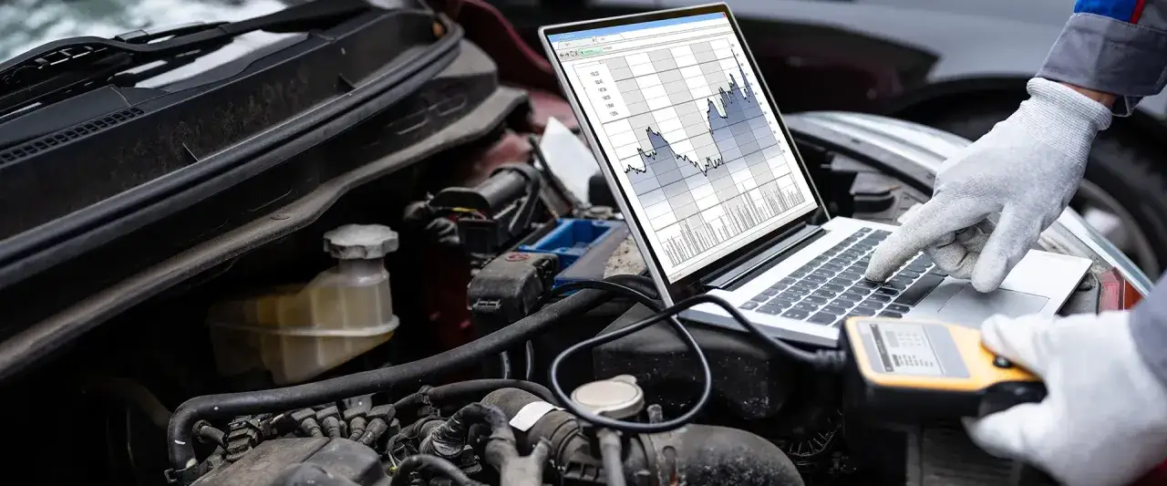 Mechanik analizuje dane z komputera diagnostycznego, sprawdzając sterownik silnika. Wykresy na ekranie pokazują parametry pracy.