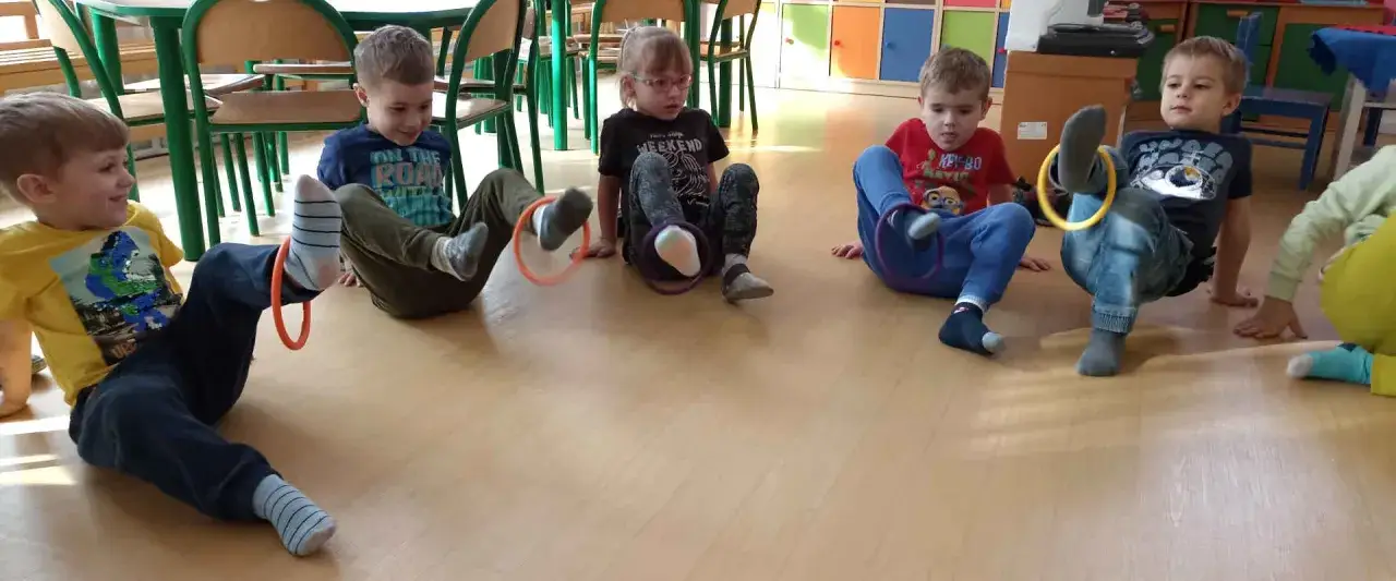 Dzieci w przedszkolu bawią się kółkami, ćwicząc koordynację. To świetne zabawy dla 6 latków w przedszkolu, rozwijające sprawność fizyczną.