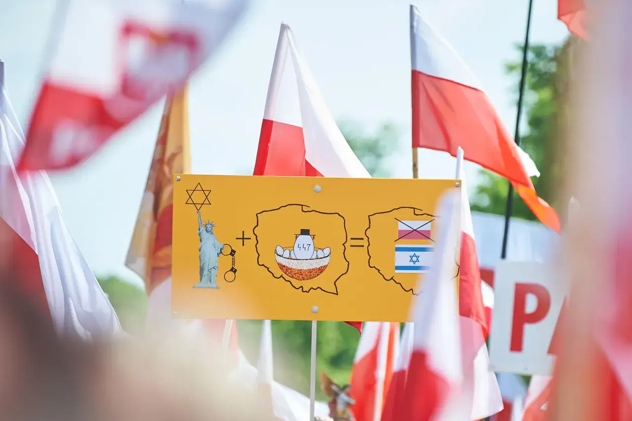 Tablica z symbolem Gwiazdy Dawida, Statuą Wolności w kajdankach, mapą Polski z napisem 