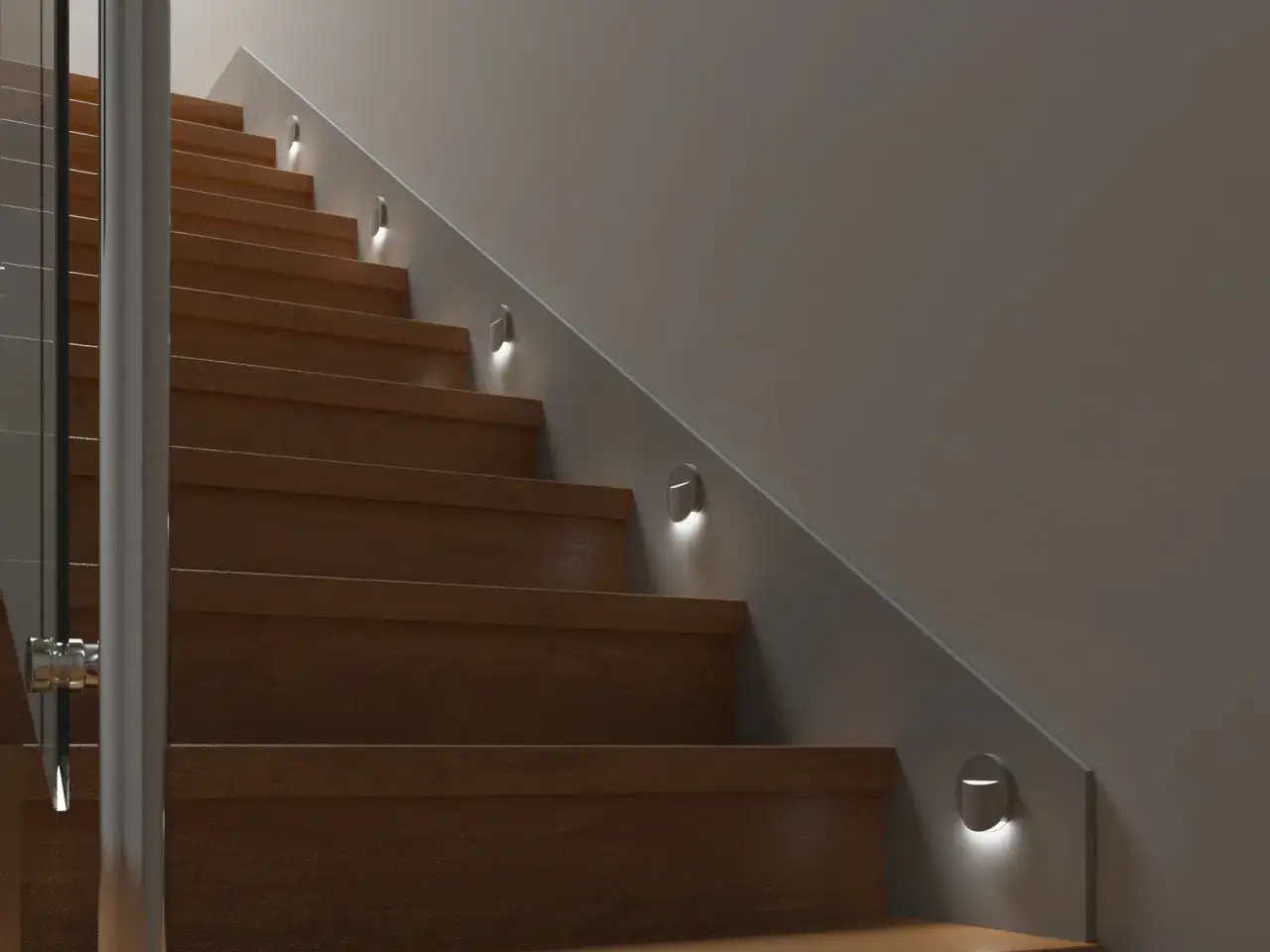 Nowoczesne schody z drewnianymi stopniami i szklaną balustradą, oświetlone dyskretnymi oprawami ewakuacyjnymi.