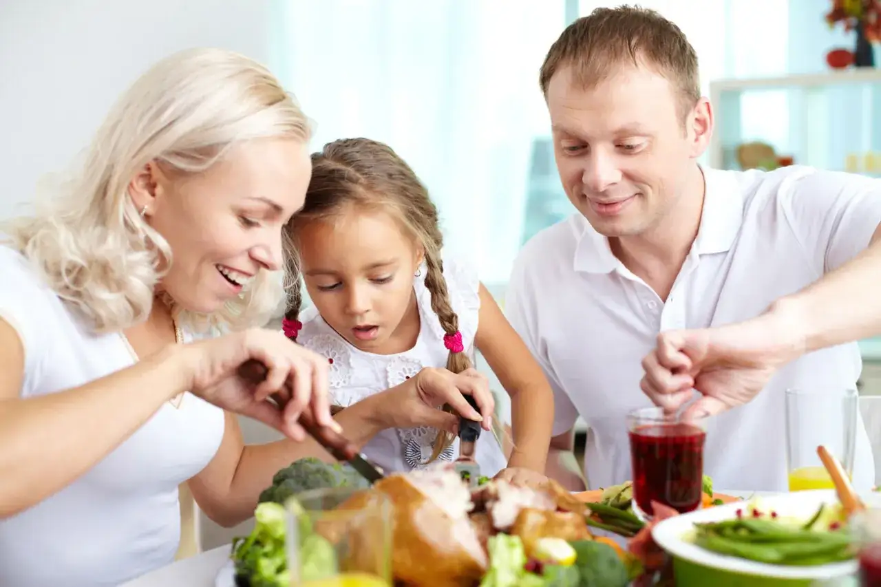 Famiglia a tavola, la bambina, un po' schizzinosa, osserva il tacchino.