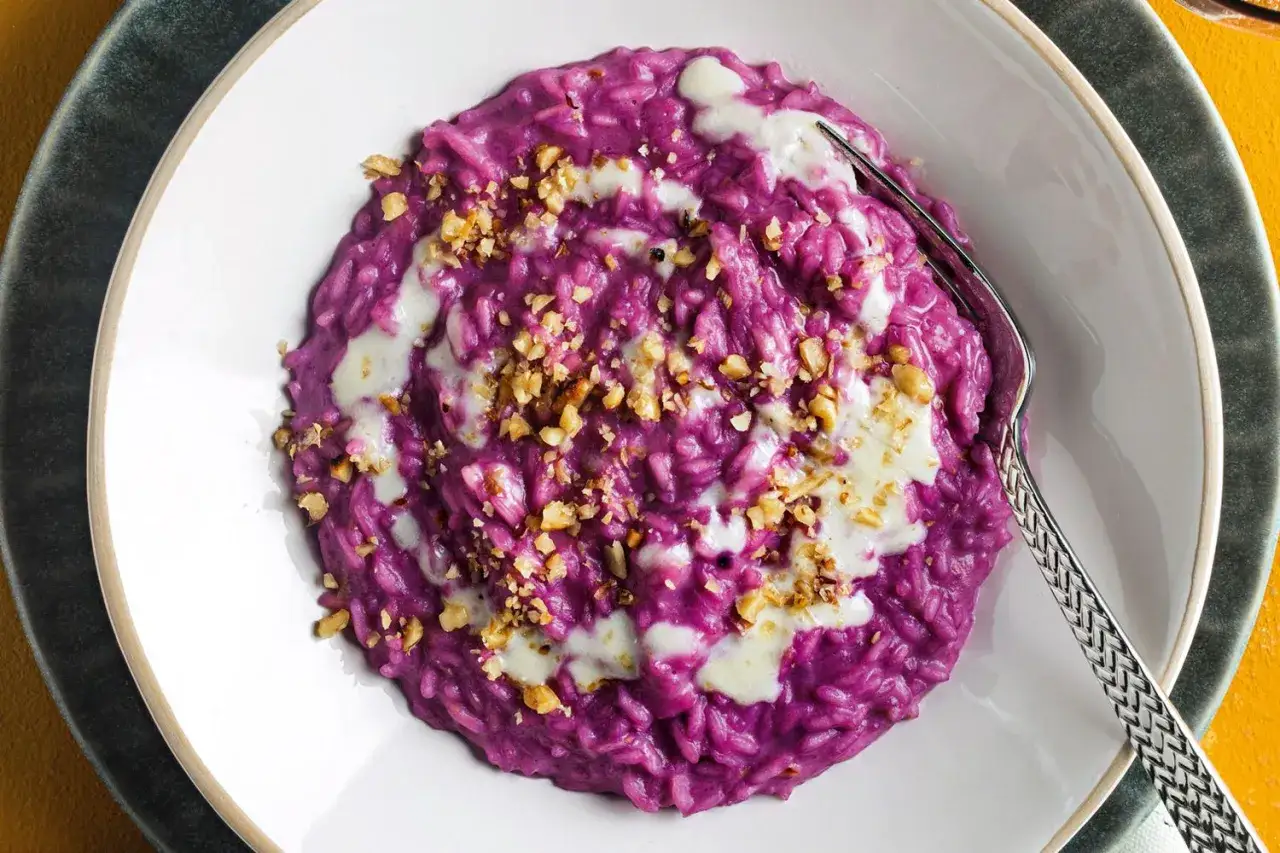 Risotto viola cremoso, arricchito da noci croccanti e un filo di formaggio fuso. Un piatto che celebra il sapore intenso del cavolo cappuccio rosso.