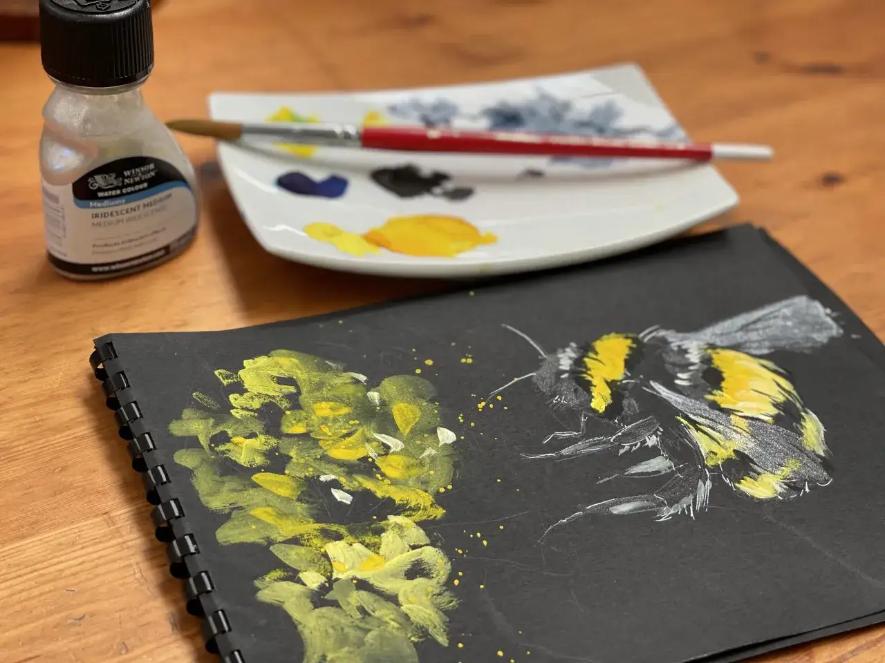 Aquarelle sur fond noir : un bourdon jaune et noir prend son envol, entour&eacute; de touches de peinture et d'un flacon de m&eacute;dium iris&eacute;.