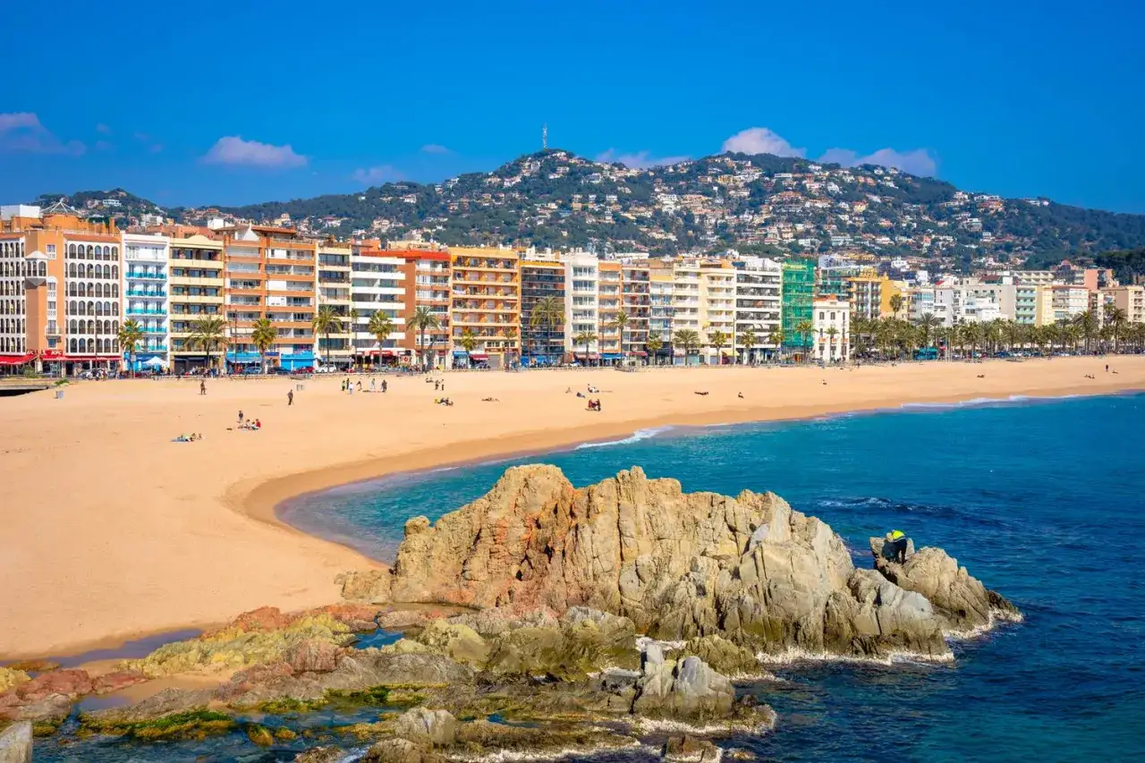 Piękna plaża w Lloret de Mar we wrześniu. Słoneczna pogoda zachęca do spacerów po piaszczystym brzegu i podziwiania turkusowego morza.