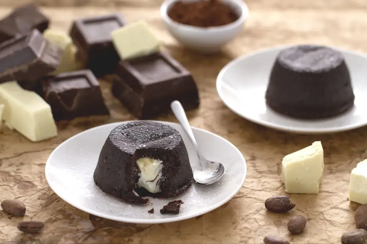 Coulant de chocolate con centro cremoso, acompa&ntilde;ado de trozos de chocolate y cacao.