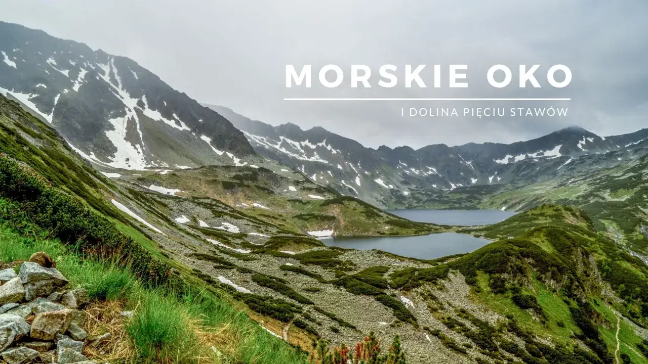 Widok na Morskie Oko i Dolinę Pięciu Stawów. Szlak prowadzi przez zielone zbocza, kamieniste tereny i ośnieżone szczyty.