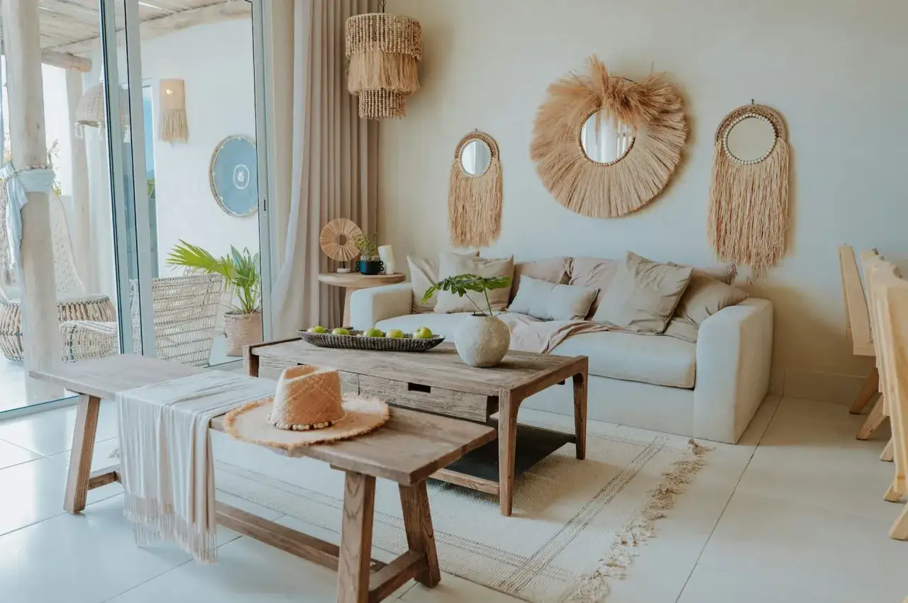 Przytulny salon w stylu boho z plecionymi lustrami, drewnianymi meblami i lnianymi tekstyliami.