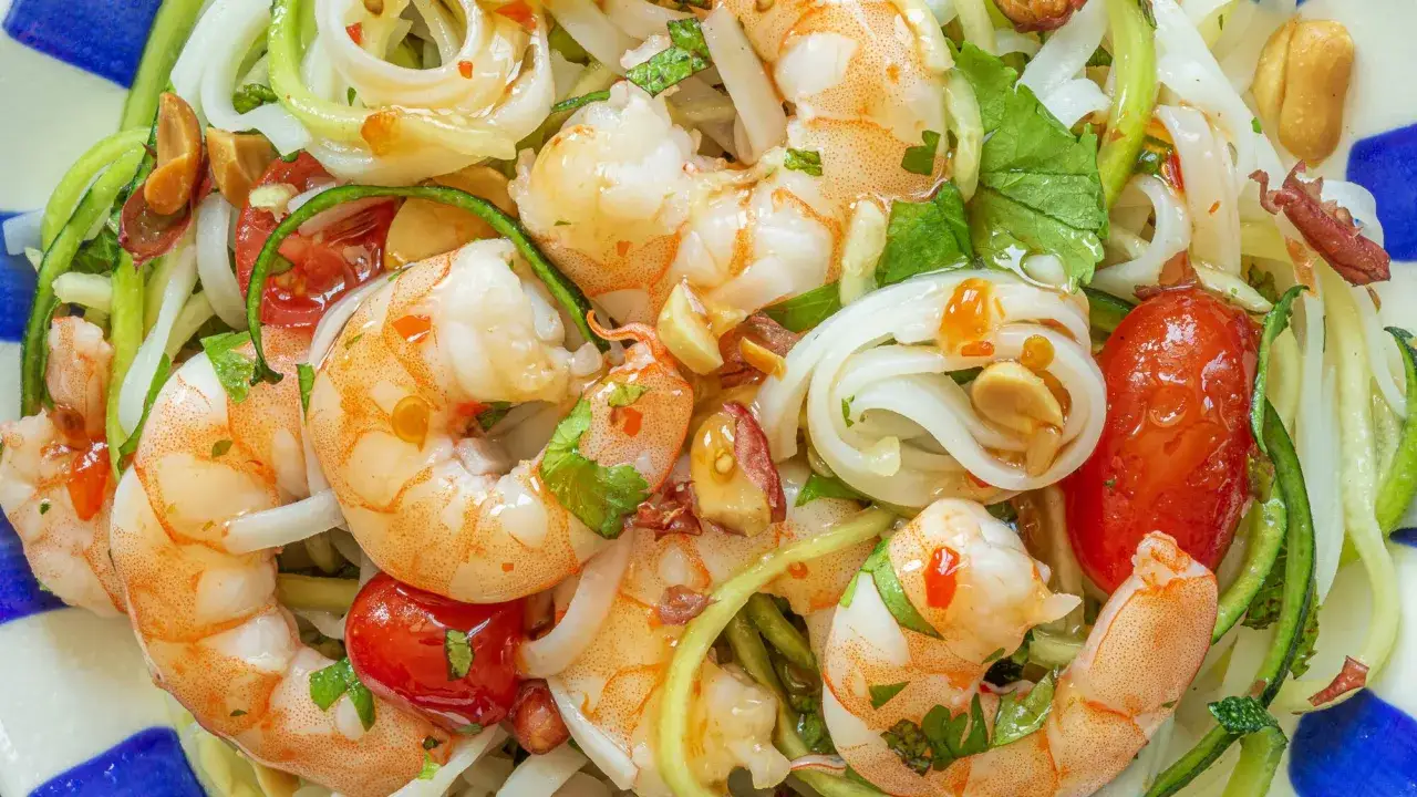 Salade de crevettes aux nouilles de riz, tomates cerises, concombre et cacahuètes.