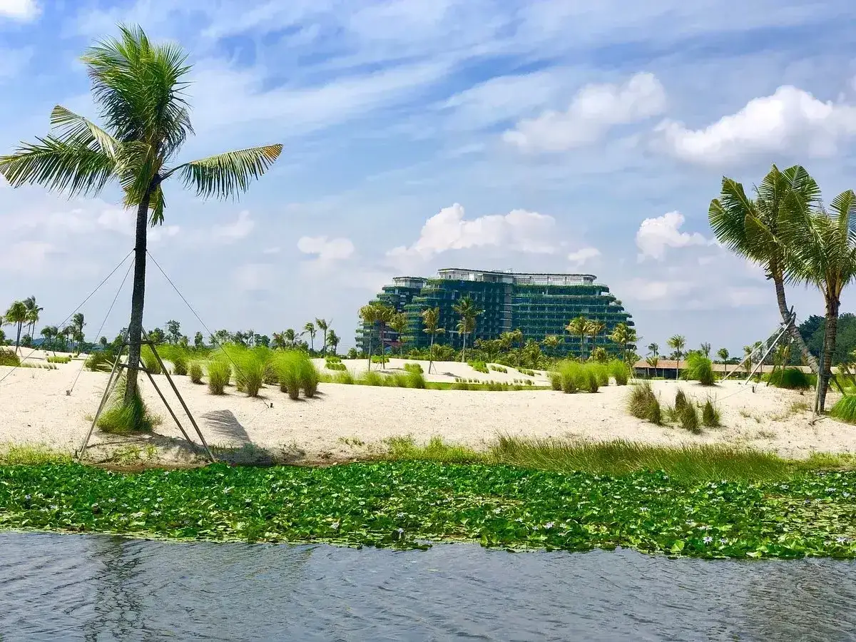 Nowoczesny hotel z zielonymi tarasami, otoczony palmami i piaszczystą plażą, tworzy unikalny krajobraz w stylu forest city Malezja.