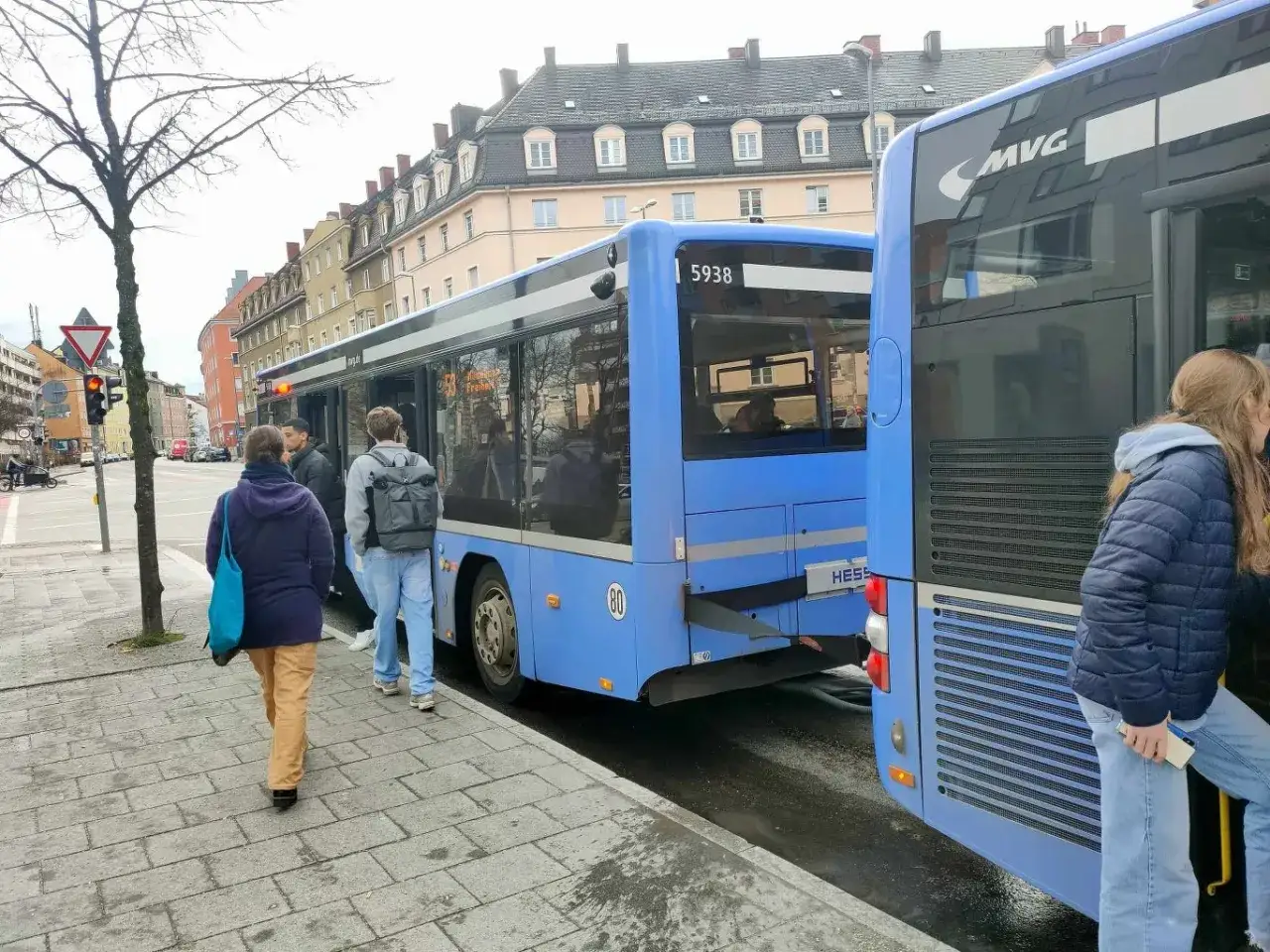Ludzie wsiadają do niebieskiego autobusu, który wygląda jak przyczepa do busa.