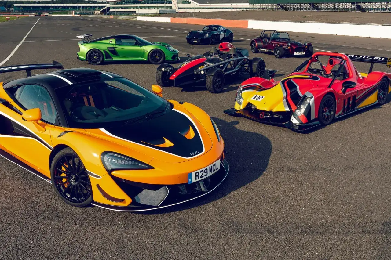 Kolekcja sportowych aut: pomarańczowy McLaren, zielony Lotus, czerwony Caterham, czarny Ariel Atom i czerwono-żółty Radical na torze wyścigowym.