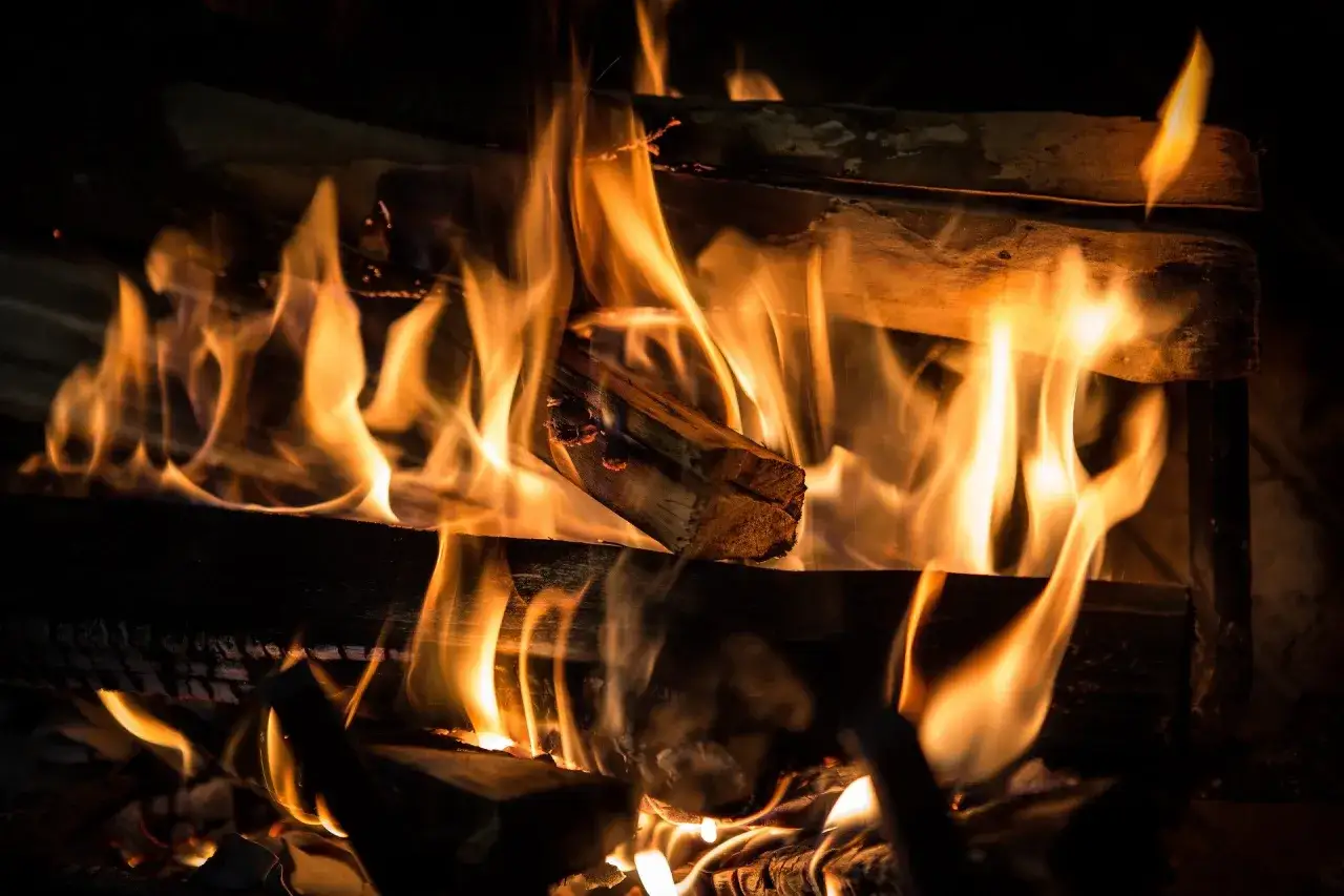 Flammen tanzen um brennendes ahornholz zum heizen. Ein gemütliches Kaminfeuer wärmt die Seele.