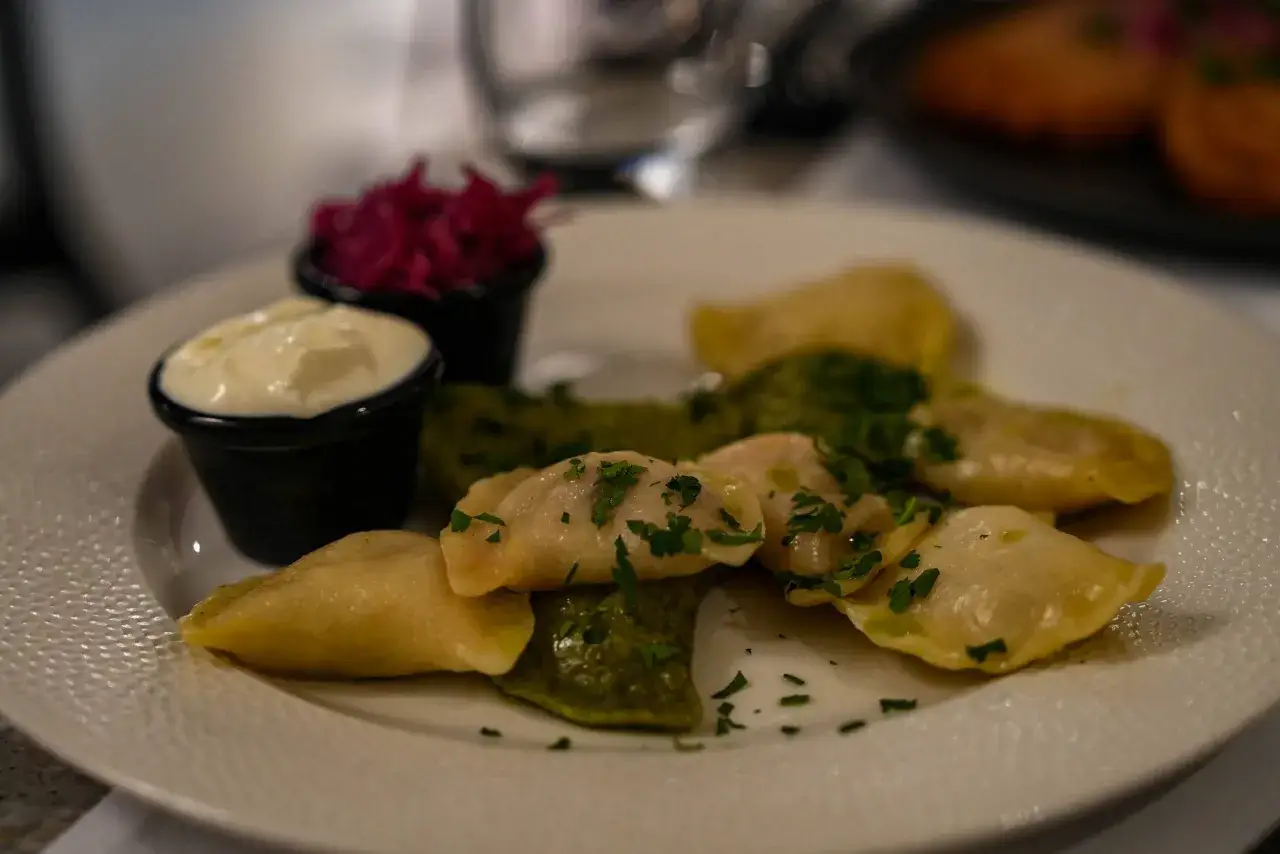 Ged&auml;mpfte Teigtaschen mit gr&uuml;ner F&uuml;llung, garniert mit Petersilie, dazu ein Klecks Sauerrahm und rote Bete. Ein k&ouml;stliches Essen in Breslau.