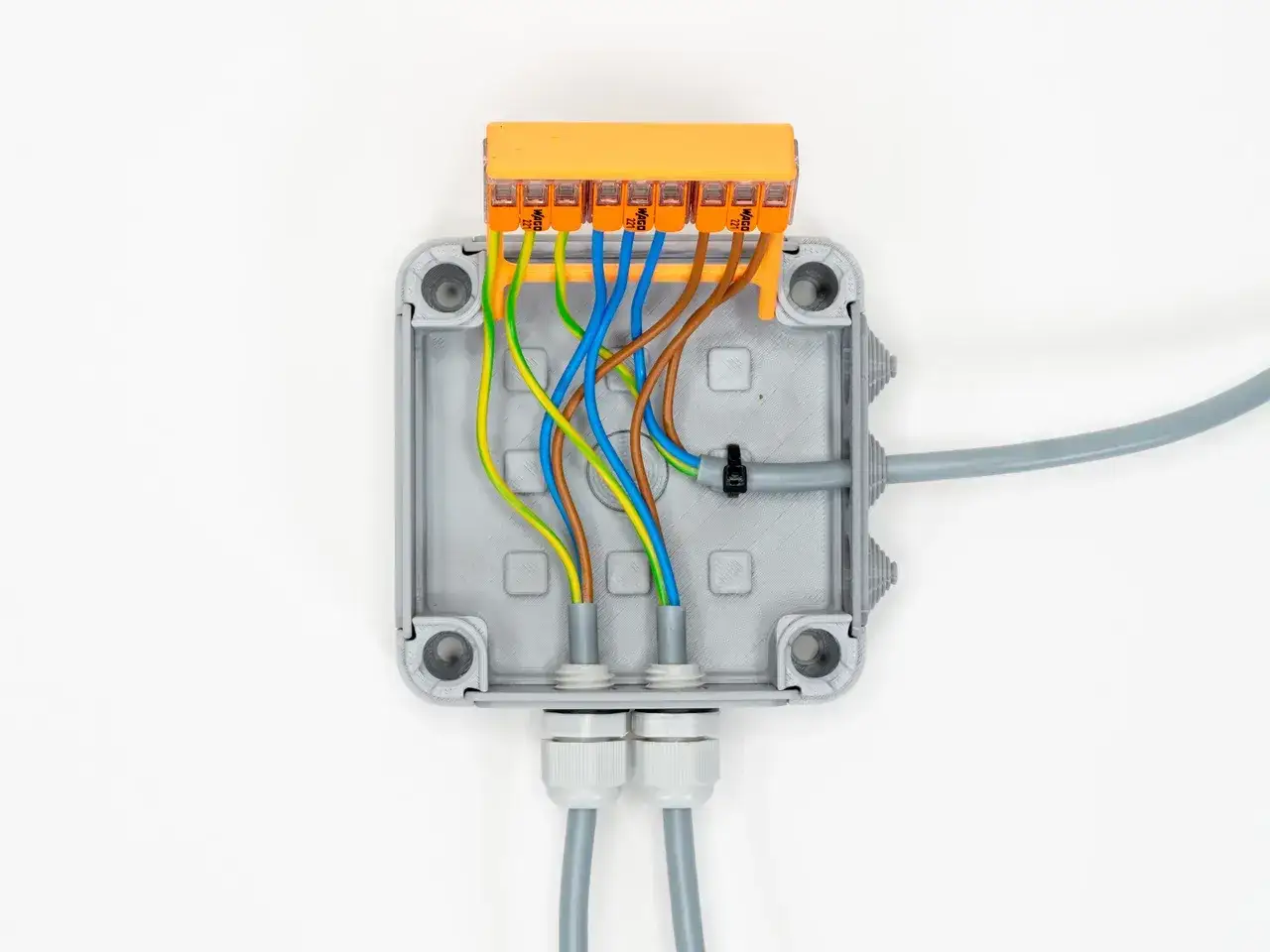 Boîtier gris ouvert avec fils colorés connectés à un domino d'électricité orange.