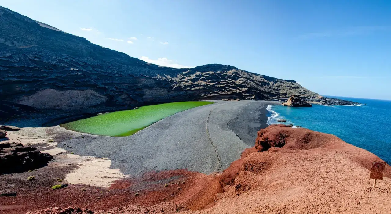 Niezwykła plaża z czarnym piaskiem, gdzie zielona laguna spotyka się z turkusowym oceanem. Wulkaniczne krajobrazy tworzą dramatyczne tło.