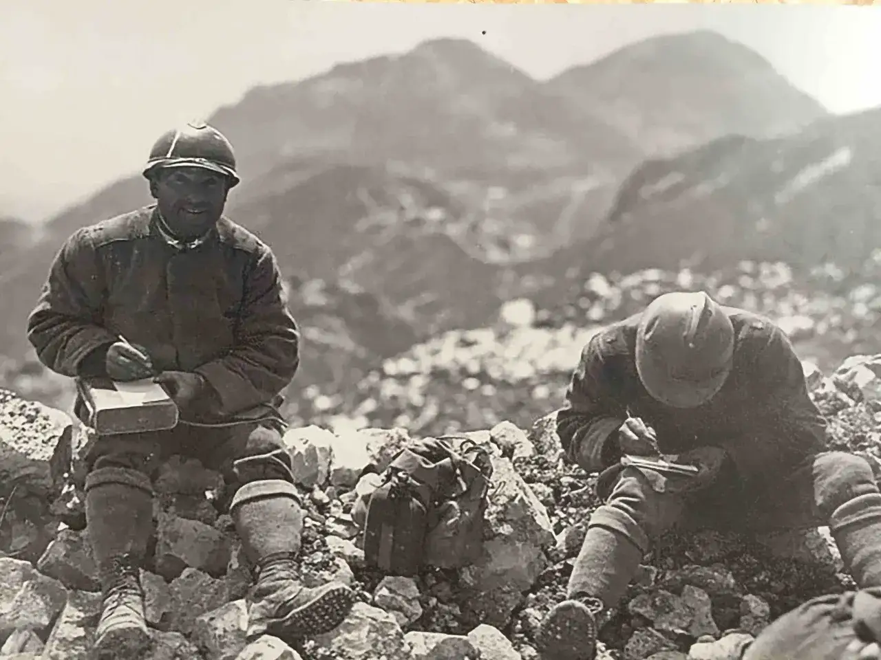 Soldati sul Monte Grappa durante la Prima Guerra Mondiale, intenti a scrivere sui loro taccuini tra le rocce.