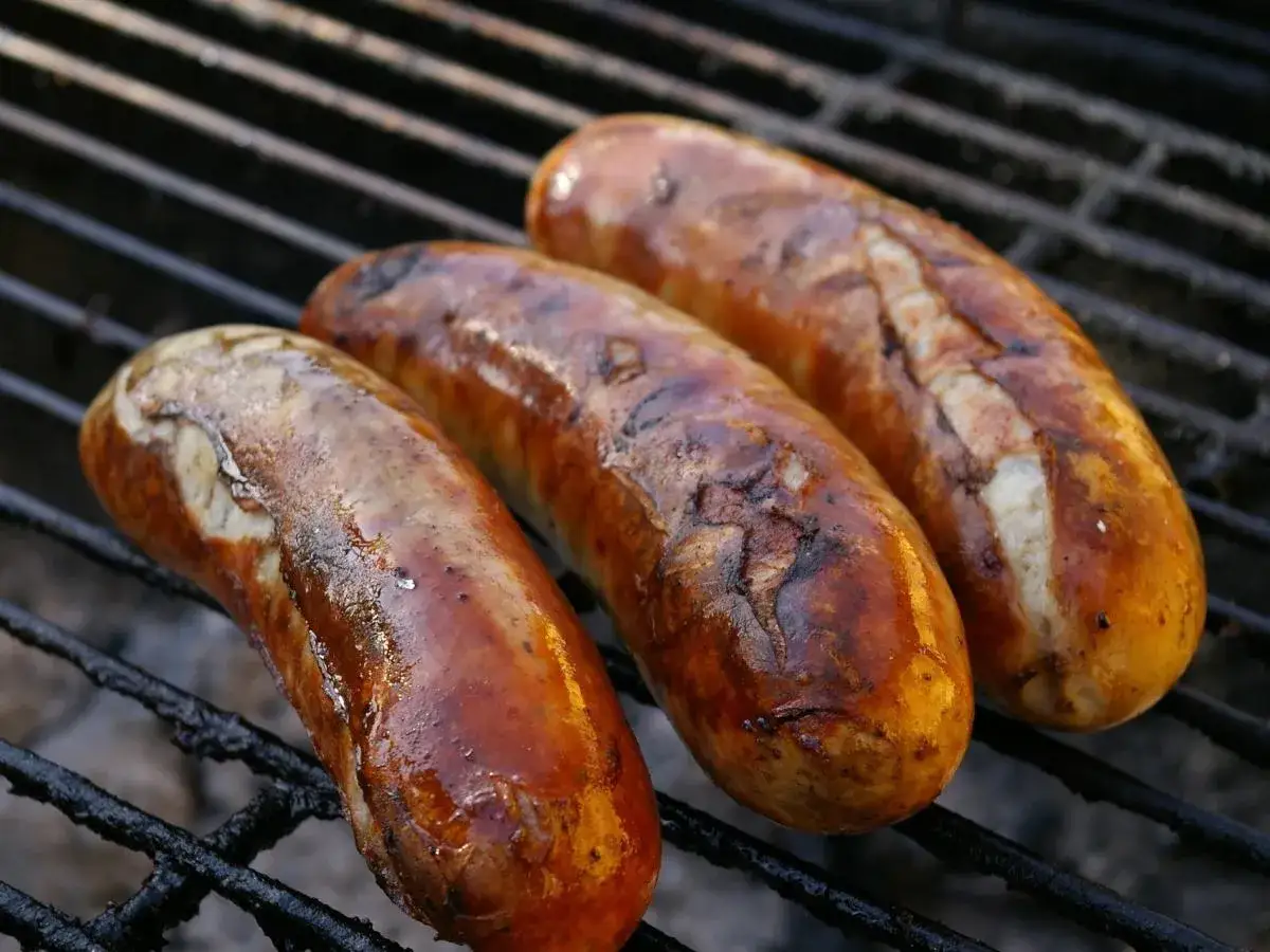 Trzy złociste kiełbaski pieką się na grillu. Czy można gotować zamrożoną kiełbasę? Tak, a efekt może być równie pyszny!