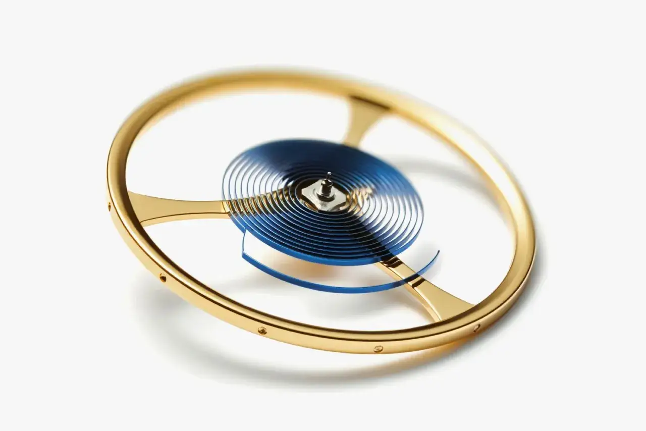 Il bilanciere di un orologio, con la sua spirale blu e la ruota dorata, cuore pulsante della precisione.