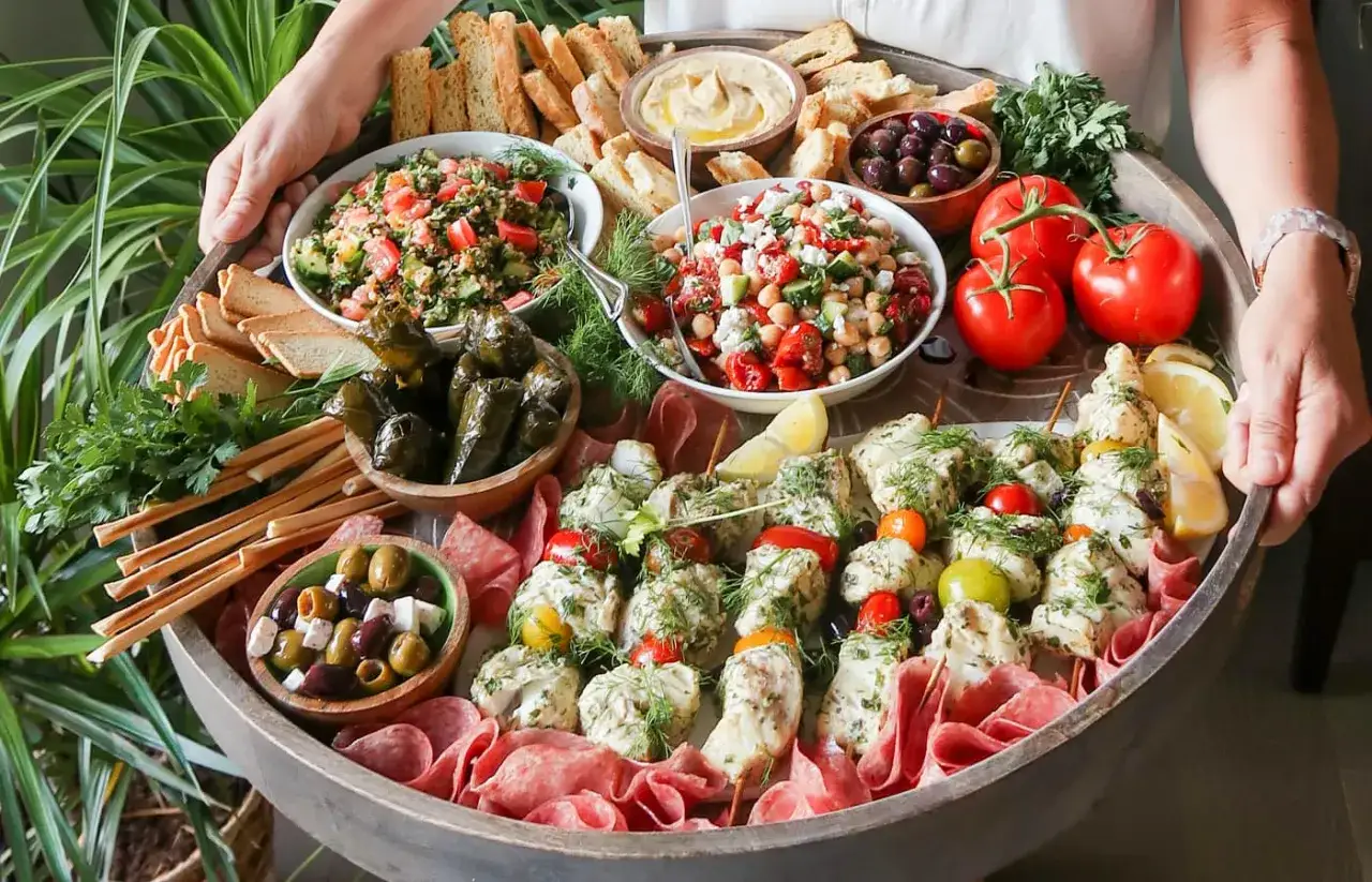 Un plateau généreux avec brochettes de poulet, salades, olives, tomates et pain. Parfait pour trouver l'inspiration pour que cuisiner cette semaine.