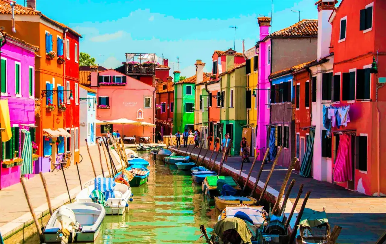 Coloratissima isola a Venezia, con case vivaci e barche ormeggiate lungo il canale.