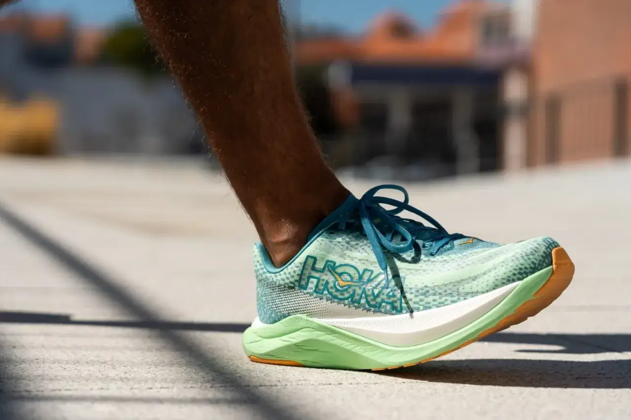 Ein Läufer testet Schuhe mit Abrollsohle. Der Hoka-Schuh in Mintgrün und Blau hat eine auffällige Sohle.